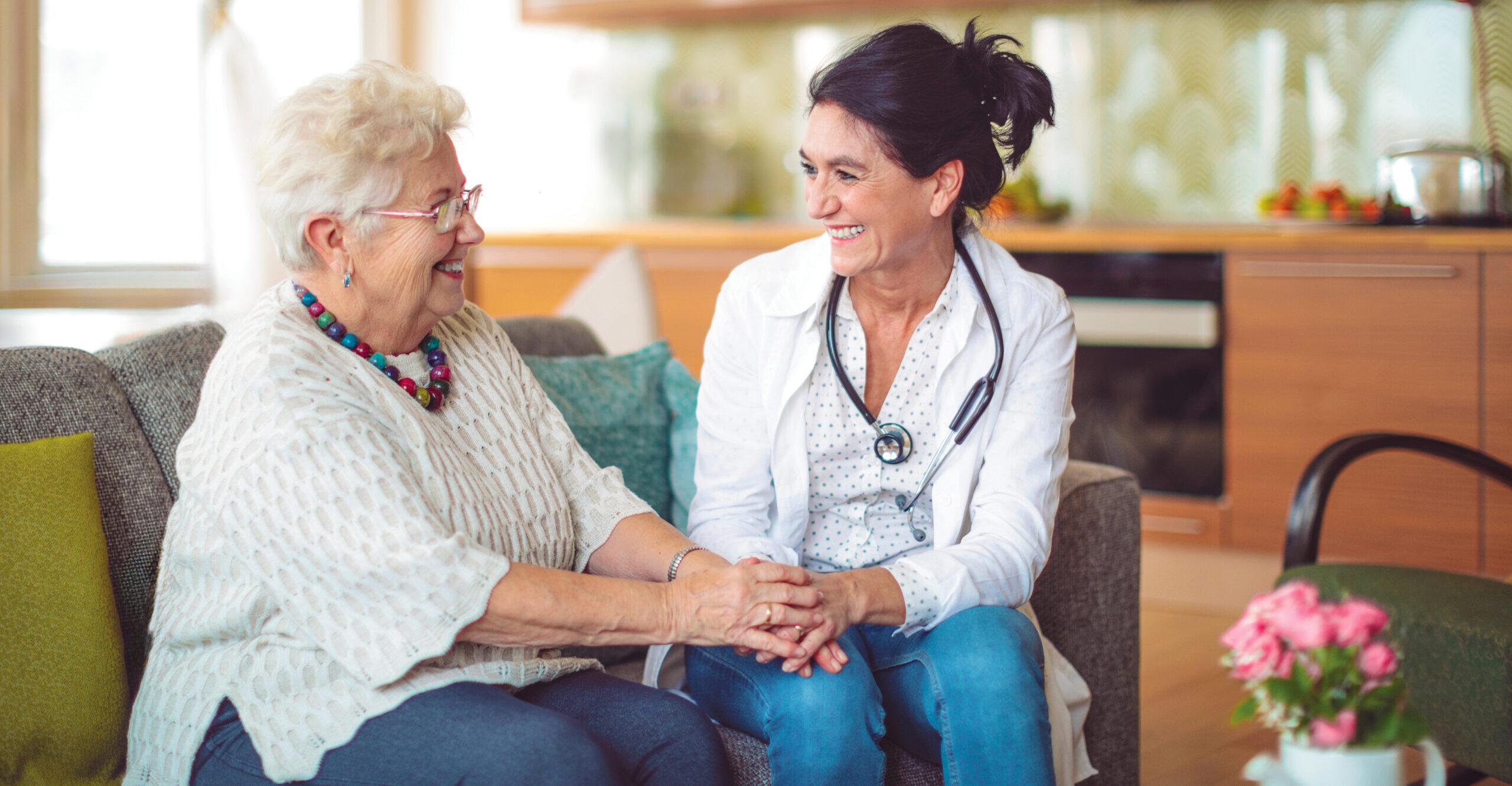 A compassionate nurse holds a senior patient’s hands.