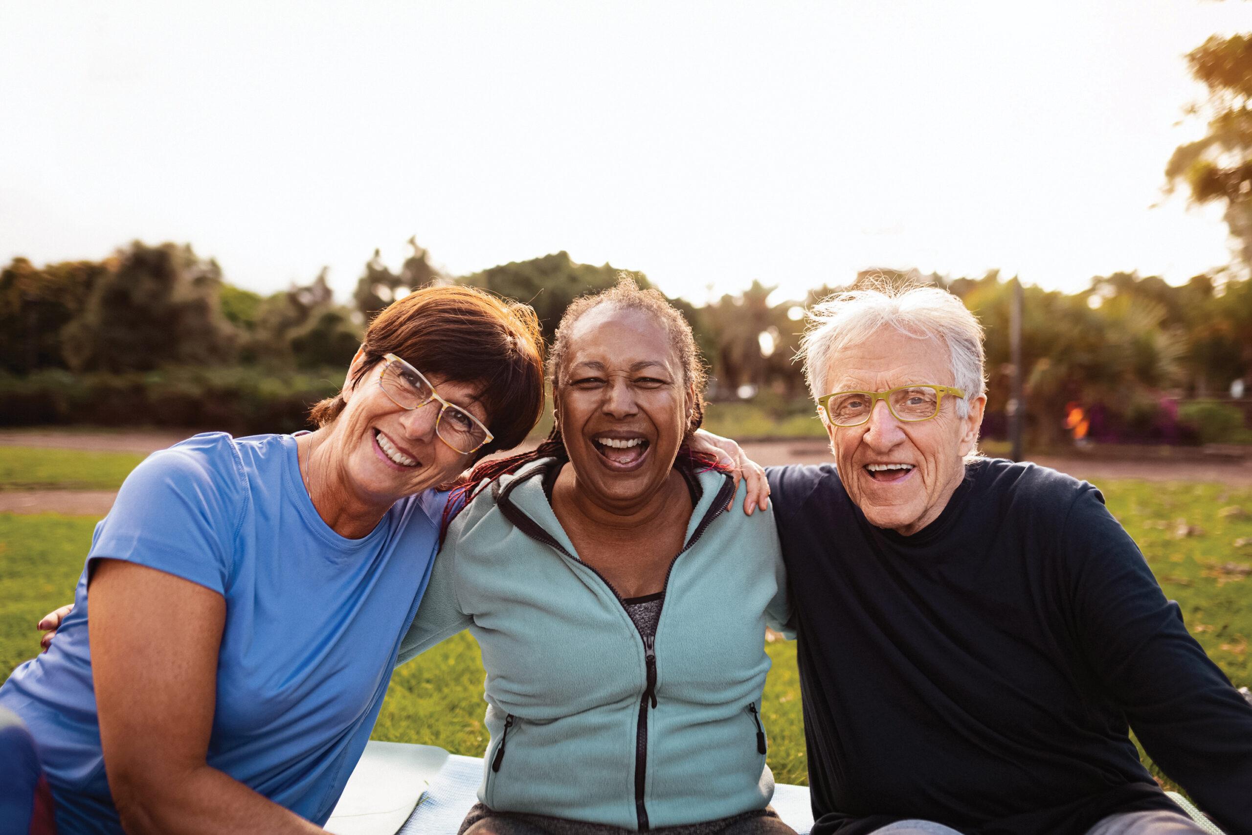 A group of three friends smiles for the camera while sitting outdoors.